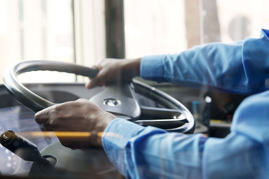 Bus driver, hands and man with public transportation, window and urban journey with commute. Person, closeup and employee for city, steering wheel and route for pickup, travel or service with safety